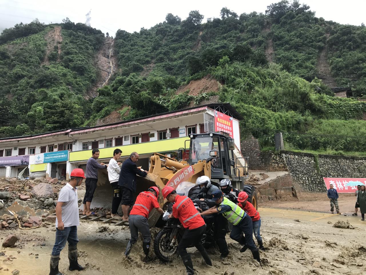 8月18日，搶險人員與民警幫助被困群眾的摩托車通過涉水路面.jpg